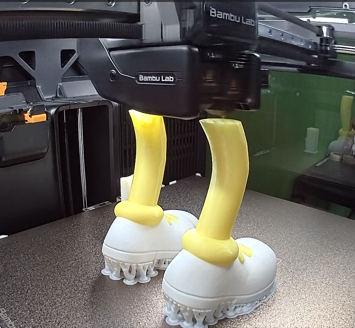 Sárga-fehér tárgyak készülnek a Bambu Lab 3D nyomtatóban